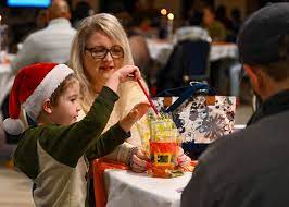 Family in restaurant, with child wearing Santa hat and pulling straw from holiday cup.