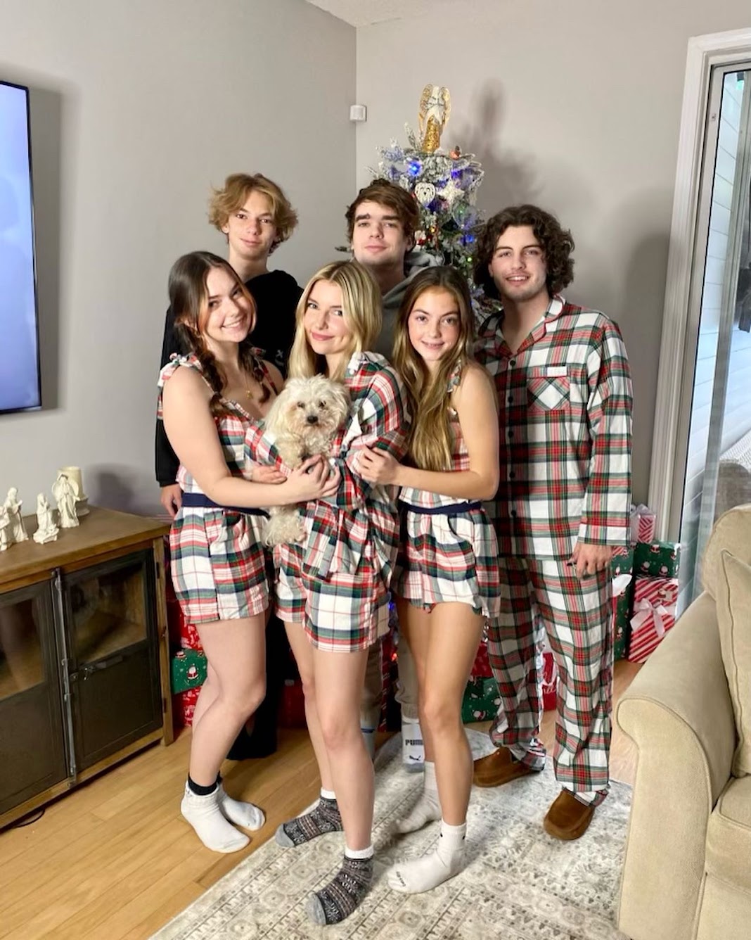 The Barry family (Mom and five teens, with long-haired little white dog) in red-plaid Christmas PJ’s