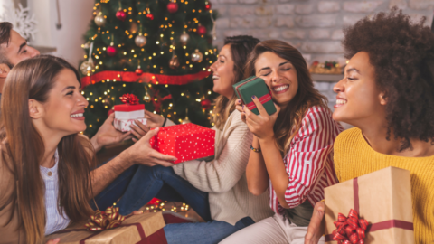 friends exchanging gifts in front of Christmas tree