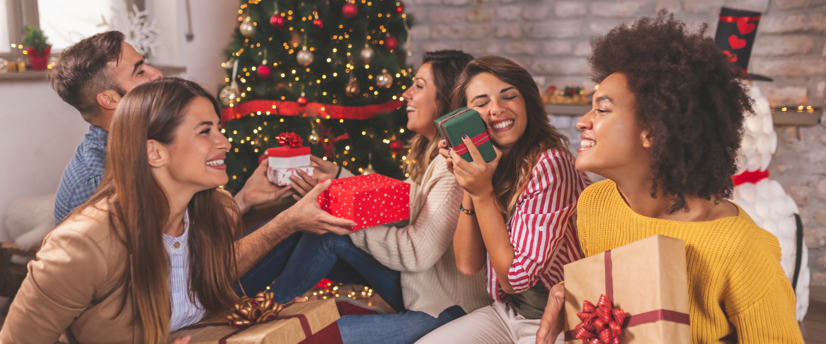 friends exchanging gifts in front of Christmas tree