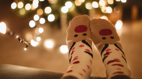 Christmas socks on feet in front of tree