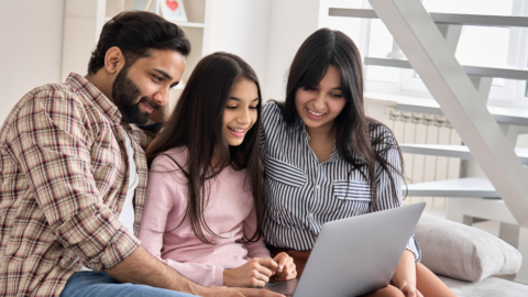 parents with adult teen daughter looking at laptop screen together