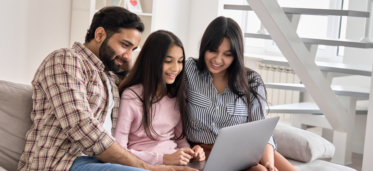 parents with adult teen daughter looking at laptop screen together