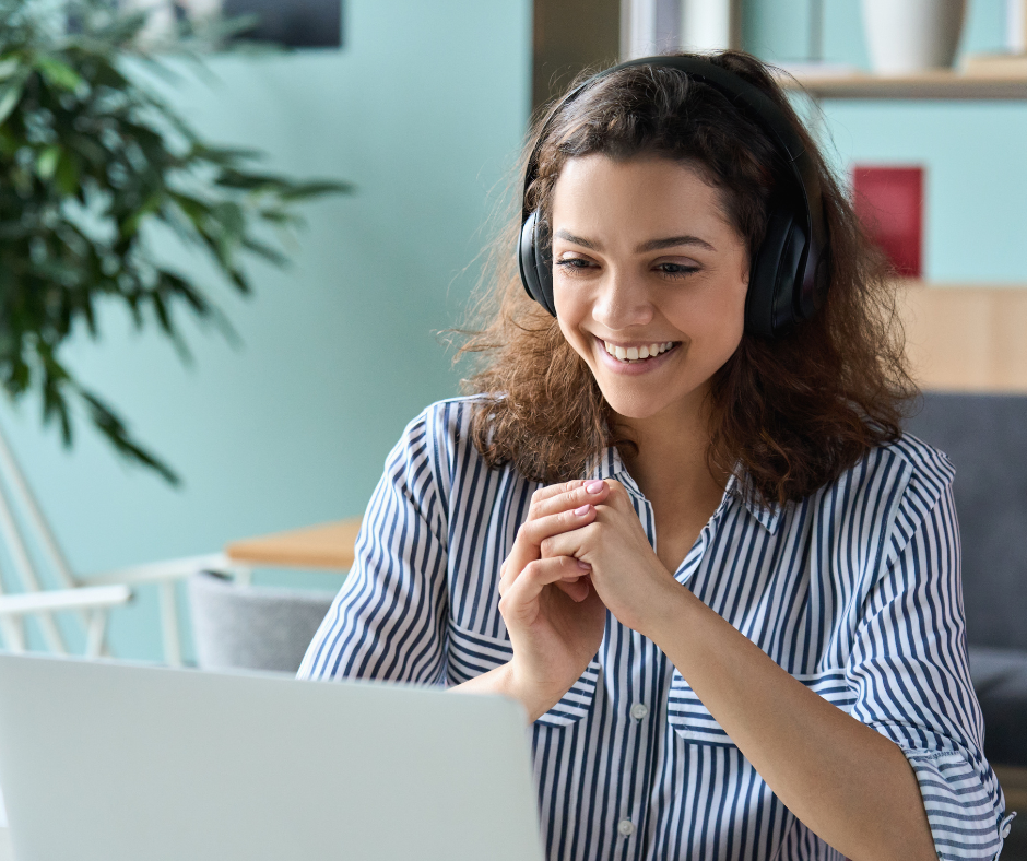 young adult women with headphones smiling at laptop