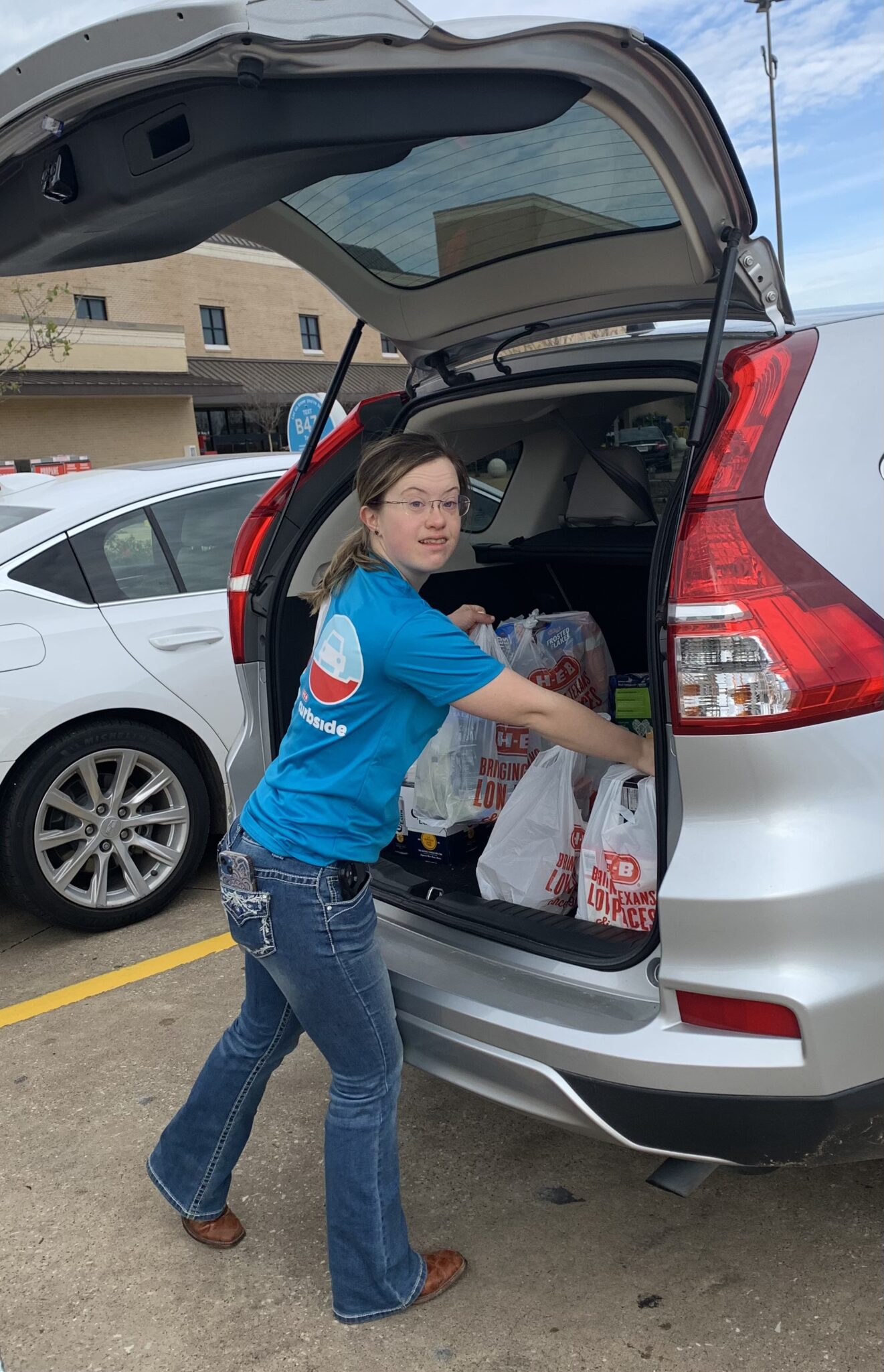 young adult girl with down syndrome loading groceries in a car