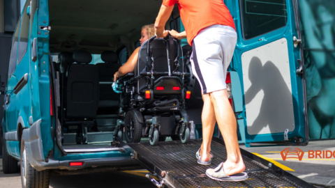 guy pushing gal in wheelchair up ramp into a van