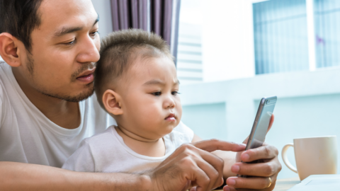 dad and toddler son looking at phone together