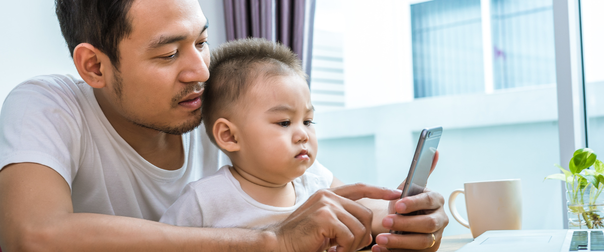 dad and toddler son looking at phone together