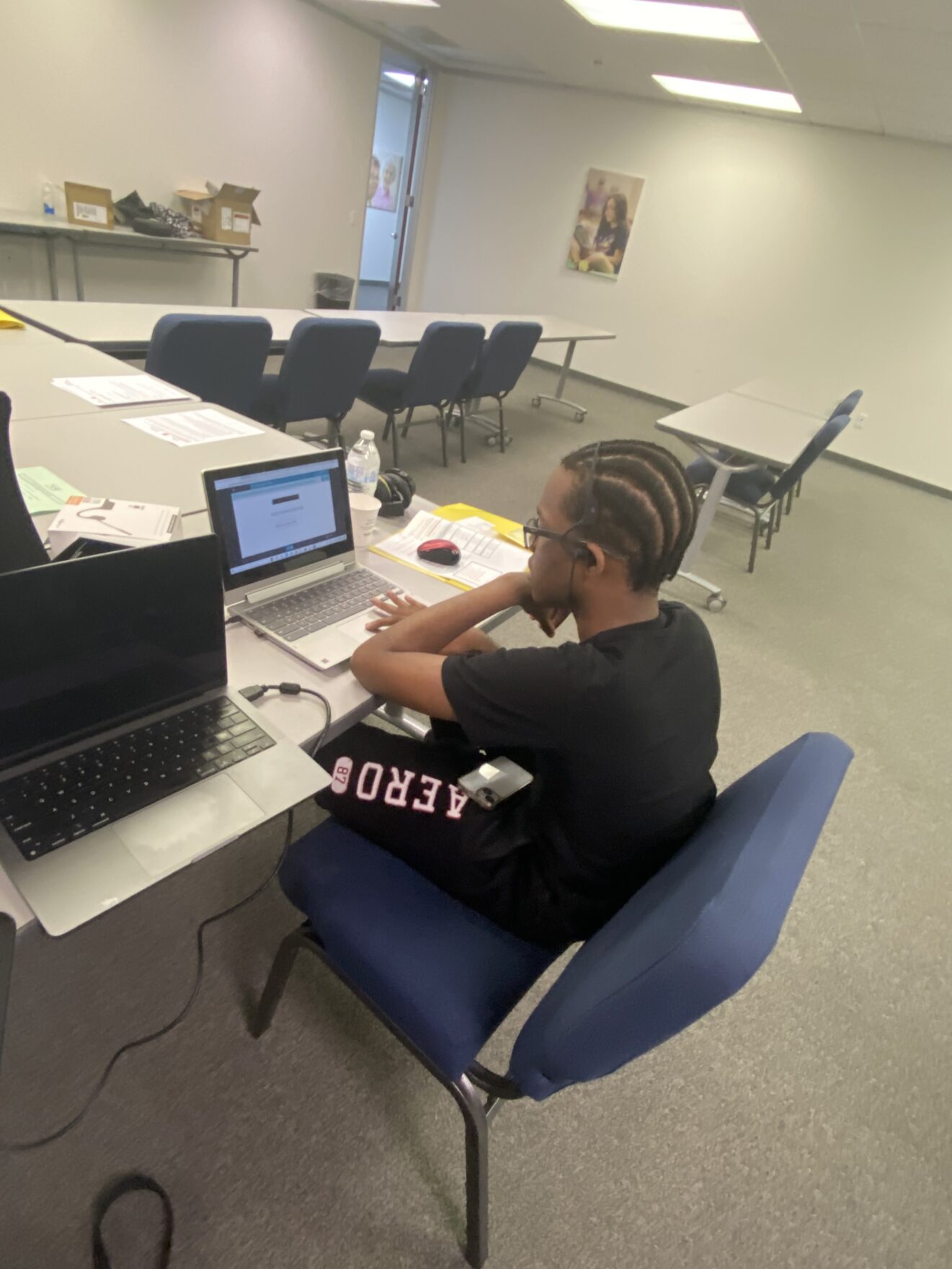 young man sitting at table using laptop in classroom