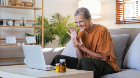 older adult woman sitting on couch communicating with laptop