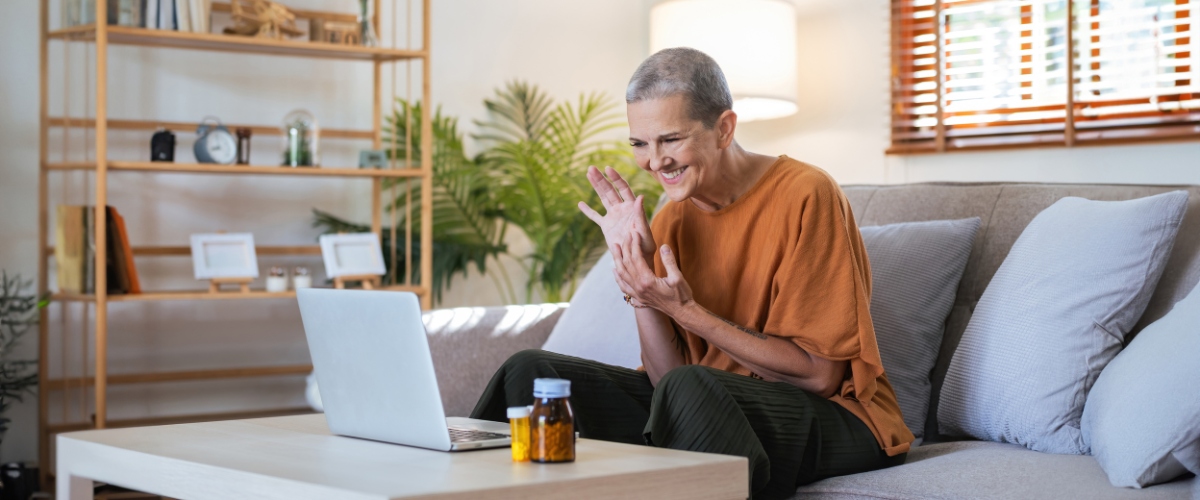 older adult woman sitting on couch communicating with laptop