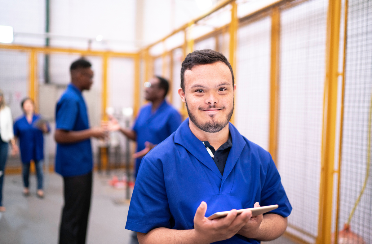 young man with down syndrome holding ipad at work