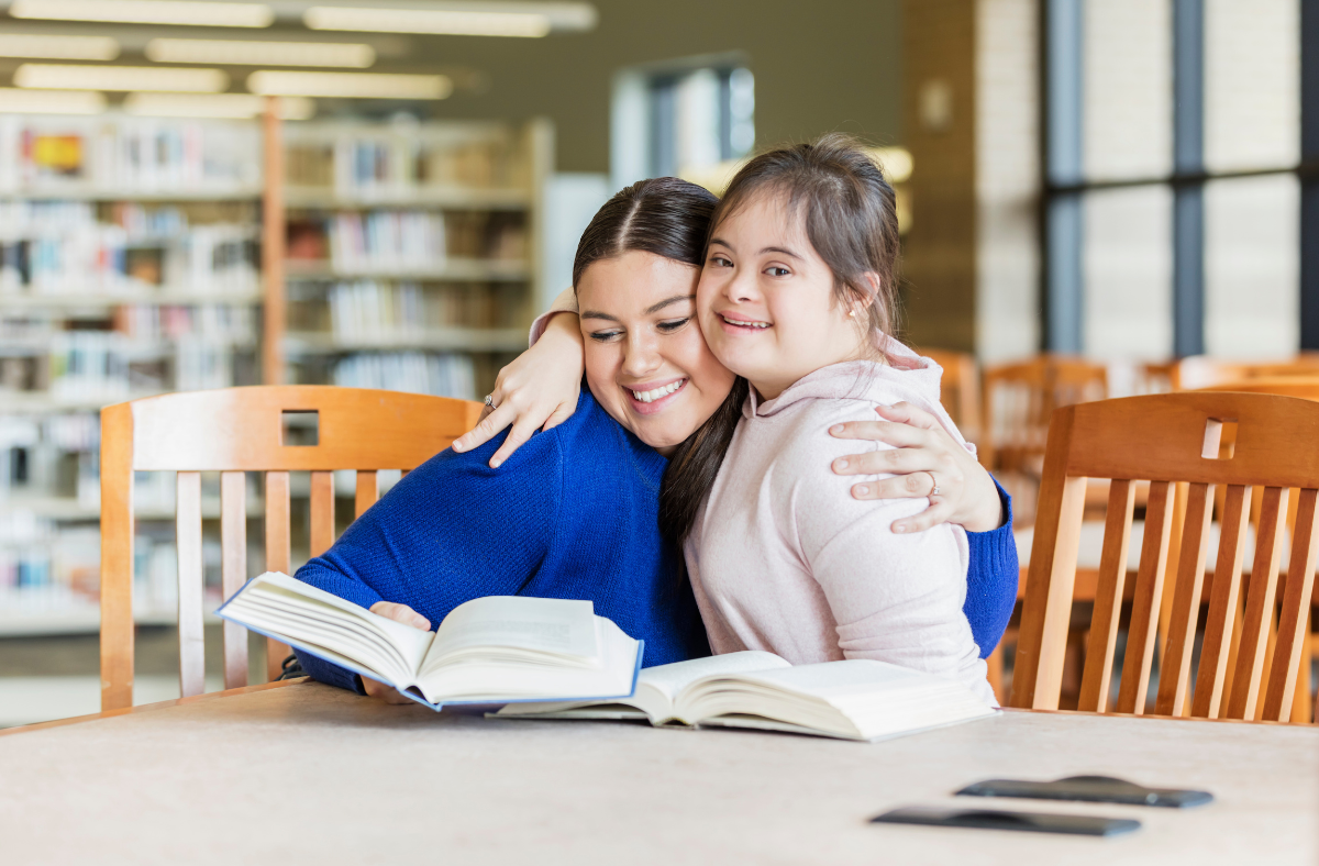  young adult girl with down syndrome hugging friend in library