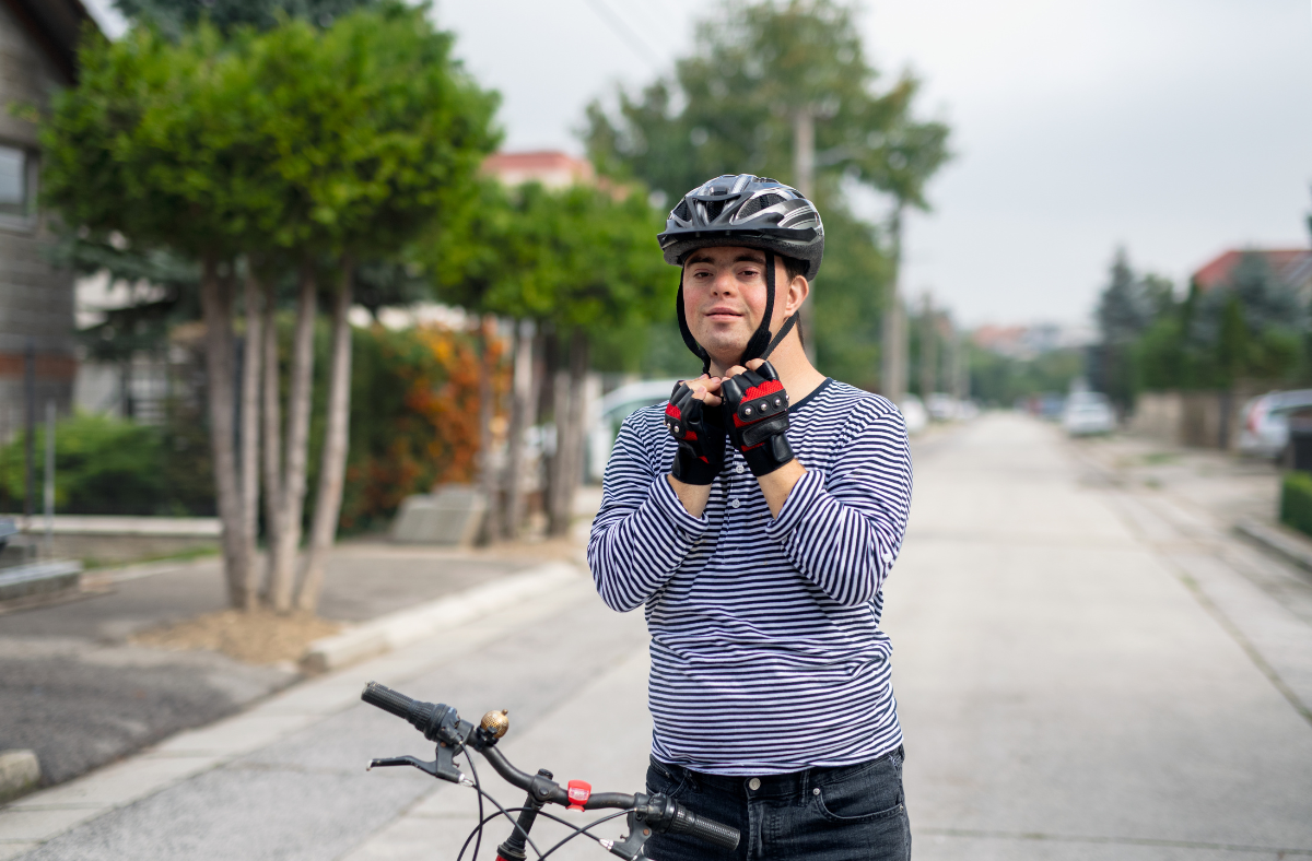 young man with down syndrome putting on bike helmet