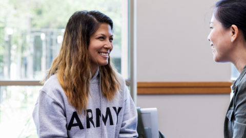 woman wearing grey hoodie talking to another women