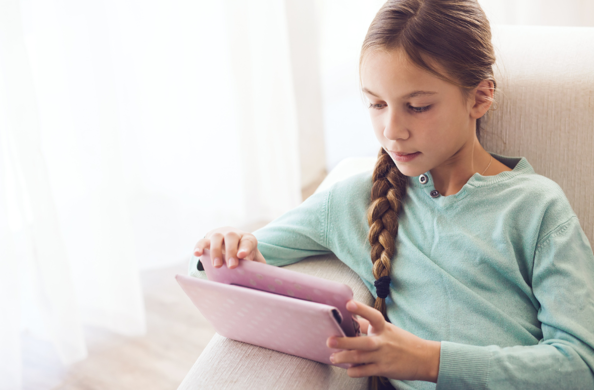 female child sitting in a chair looking at an ipad