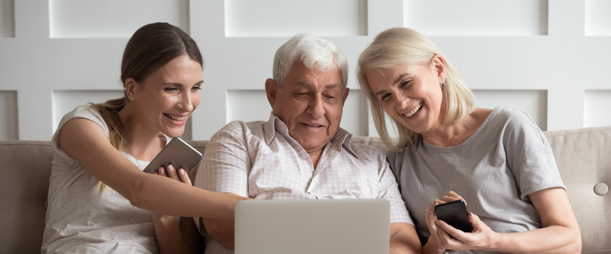 3 adults sitting on couch together looking at laptop