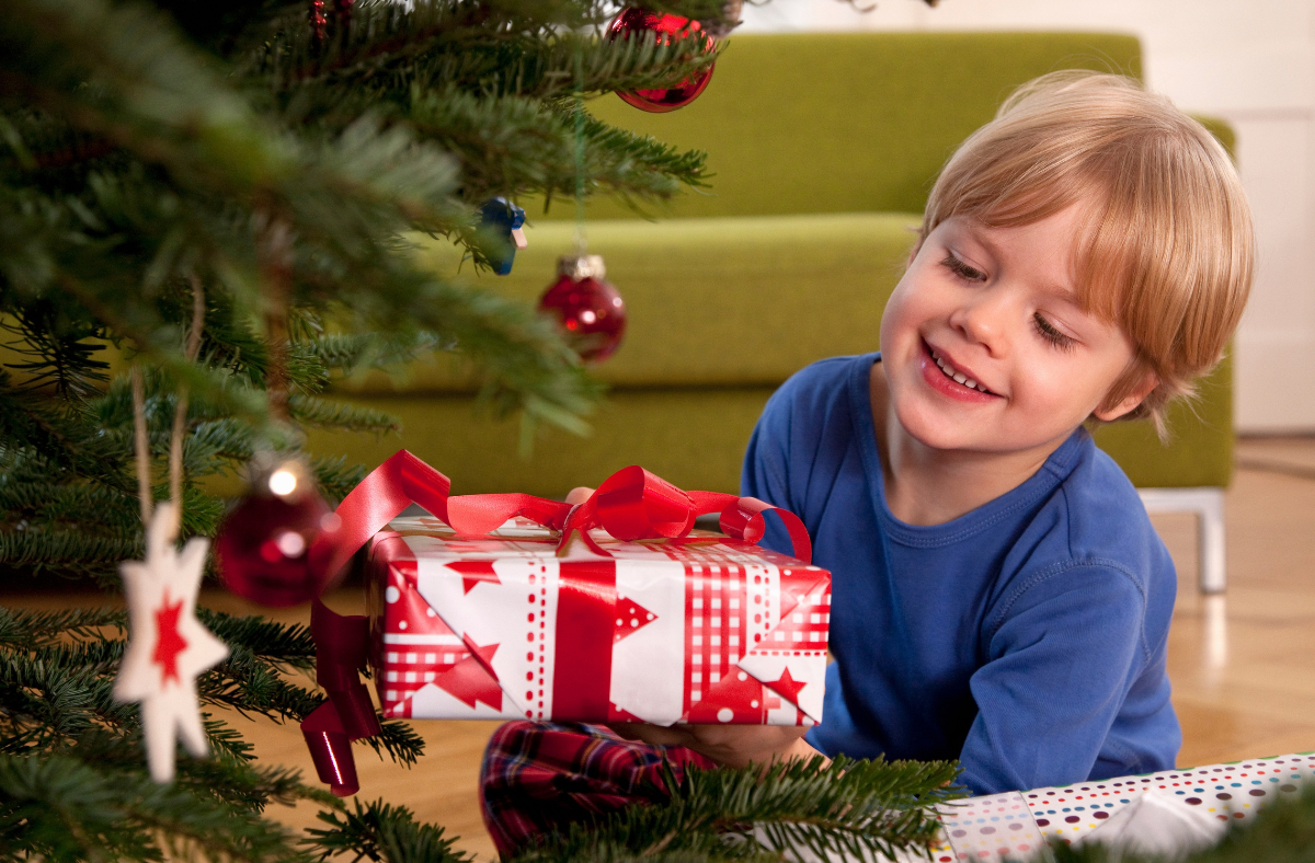 boy holding gift in front of Christmas tree