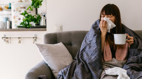 person on couch looking ill holding mug