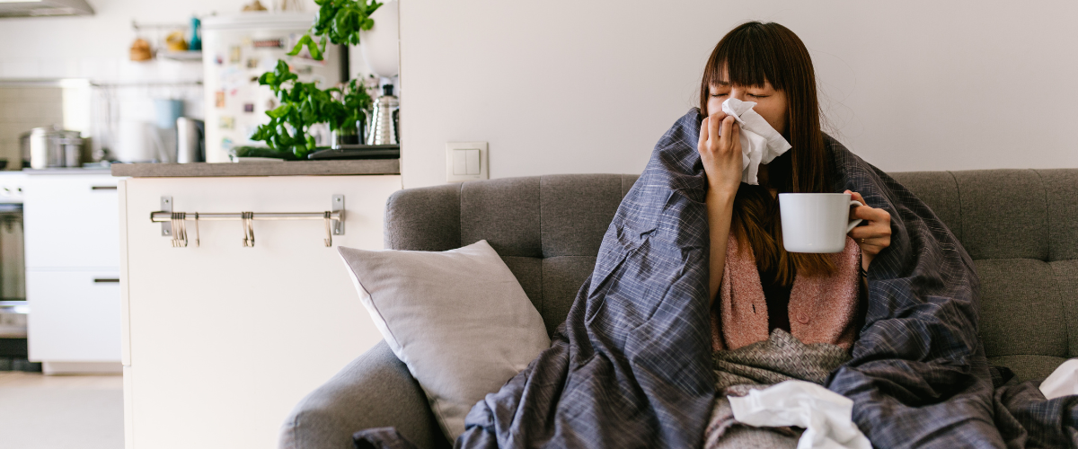 person on couch looking ill holding mug