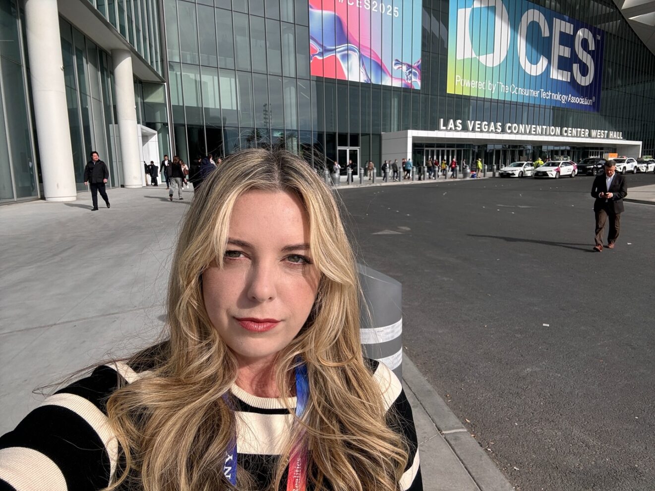 woman taking selfie in front of CES show sign
