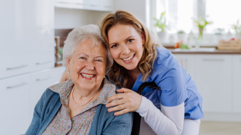 caregiver smiling with older adult woman