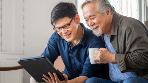 older man and younger gentlemen looking at ipad together and smiling