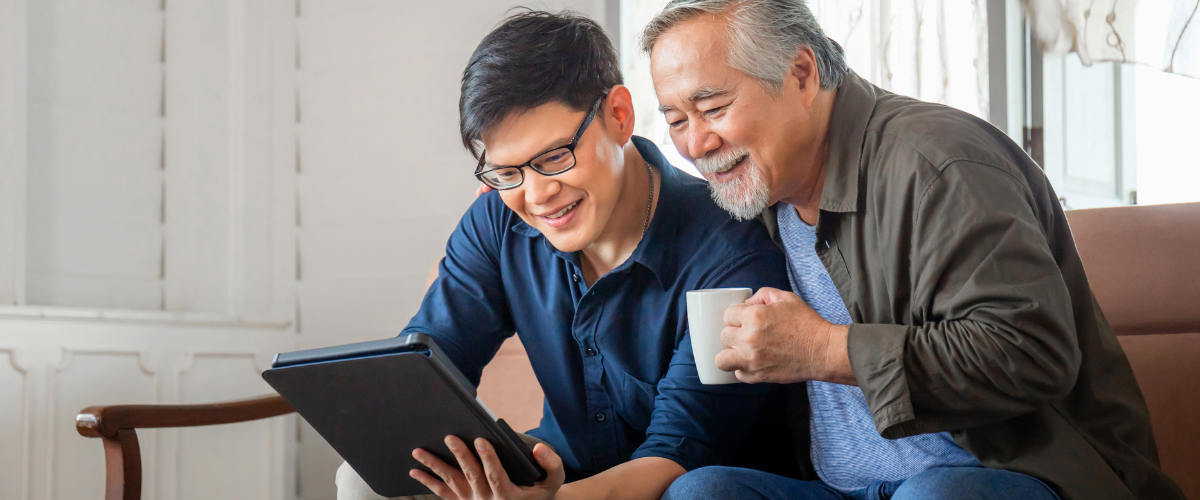 older man and younger gentlemen looking at ipad together and smiling