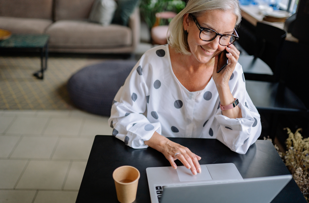 woman with phone to her ear typing on laptop