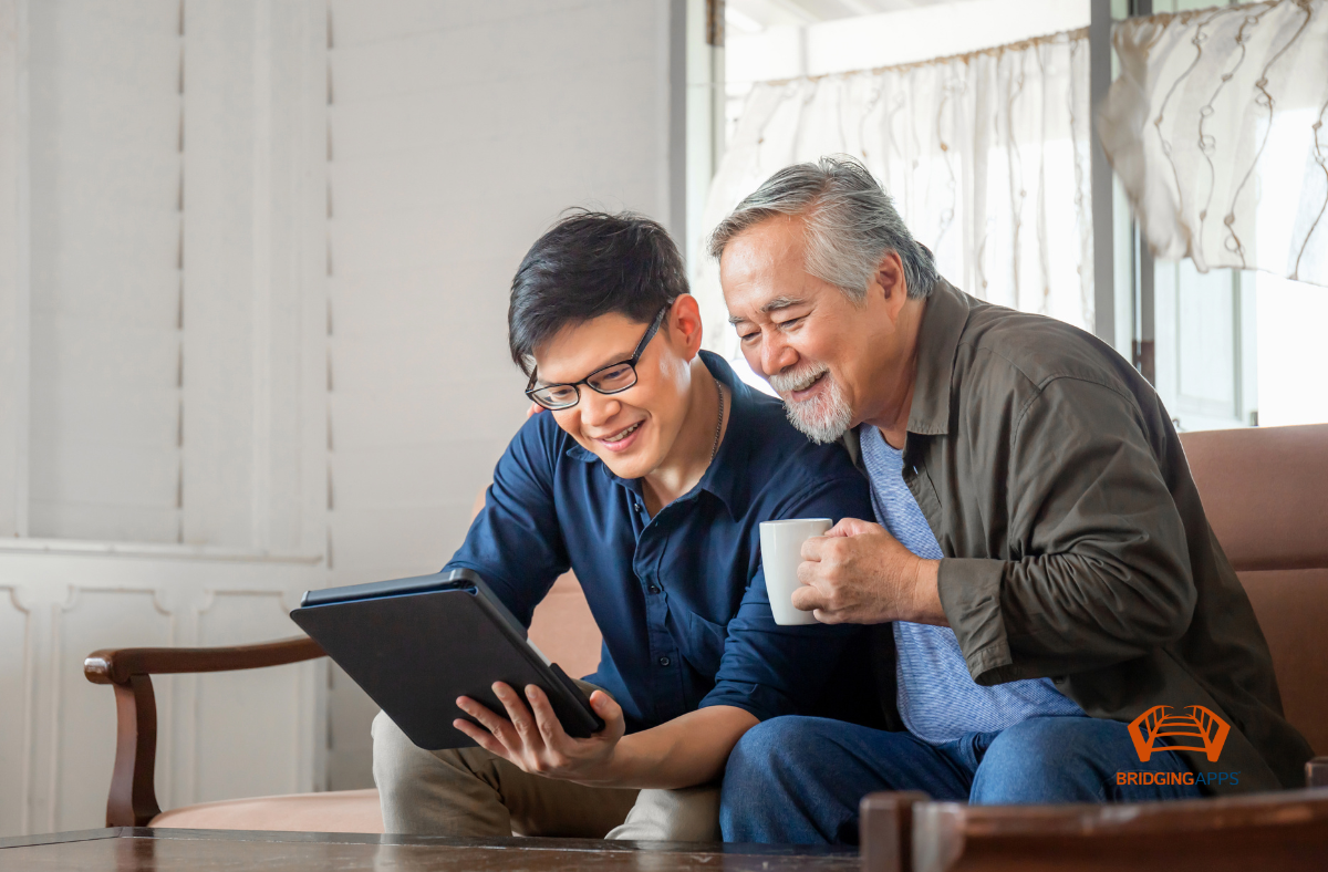 older adult man with young man, both looking at laptop