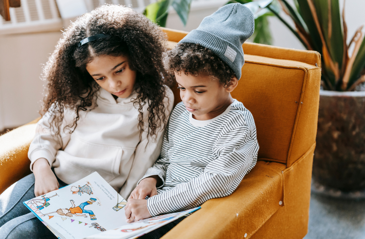 2 children sitting in chair reading a book together