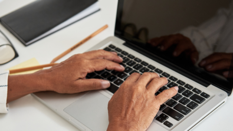 older adult hands typing on laptop