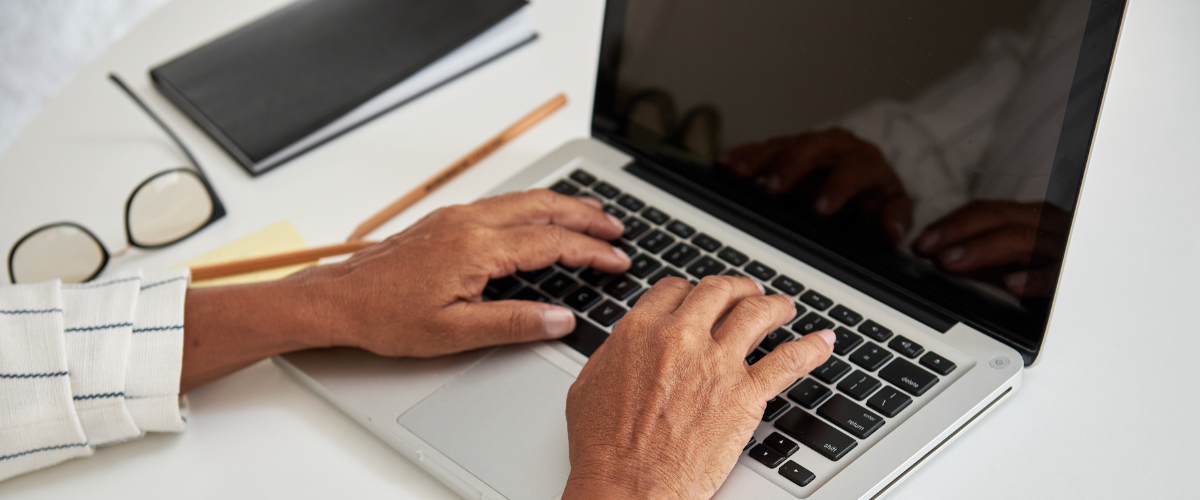 older adult hands typing on laptop