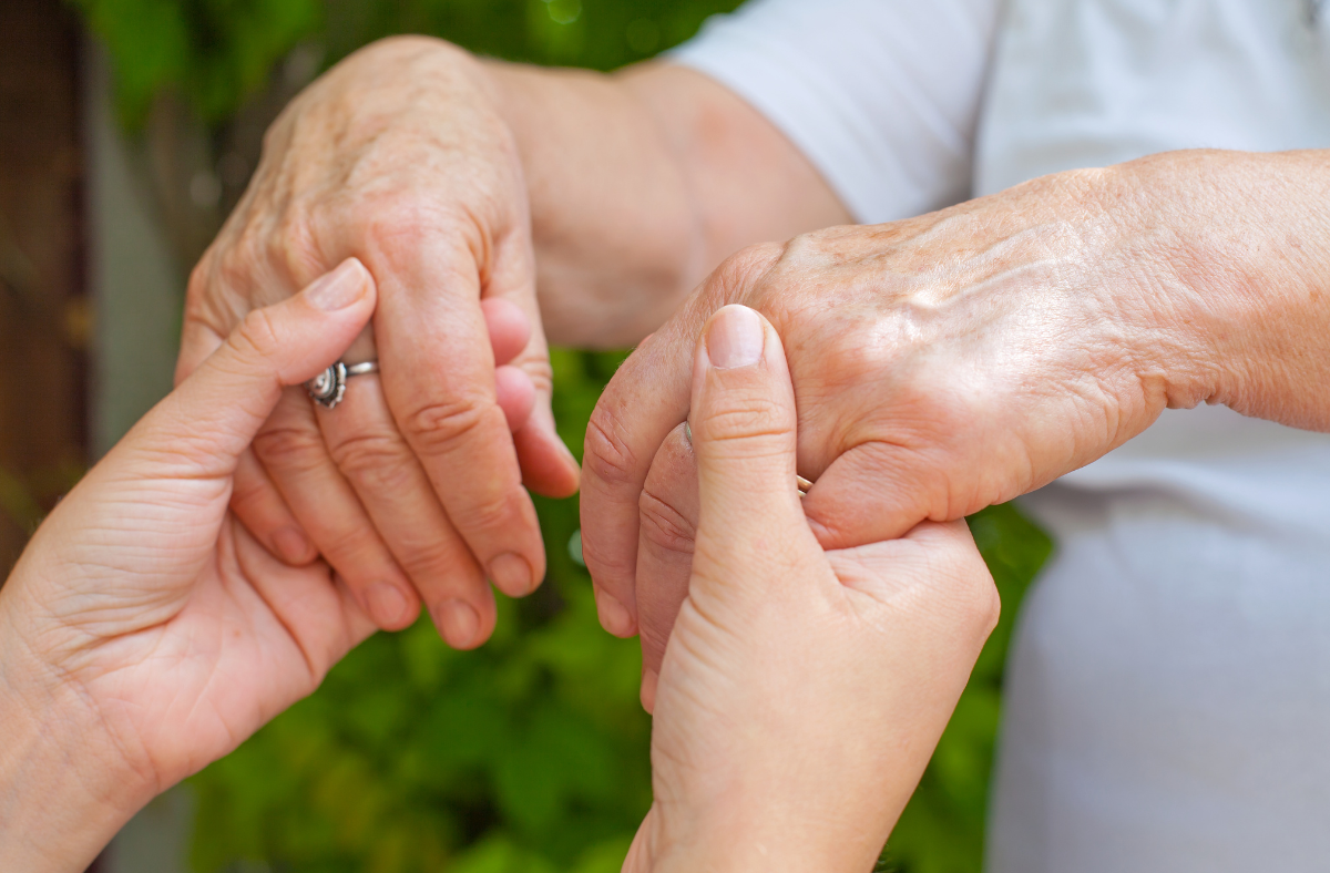 young adult hands holding older adult hands
