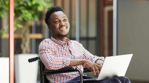 smiling man in wheelchair holding laptop