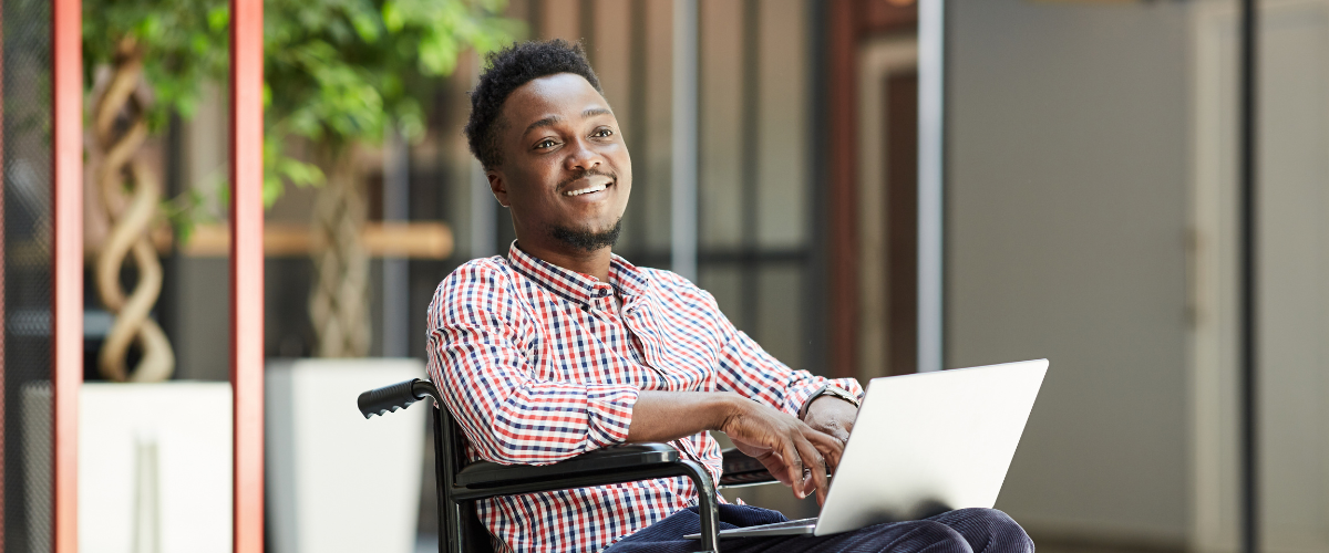 smiling man in wheelchair holding laptop