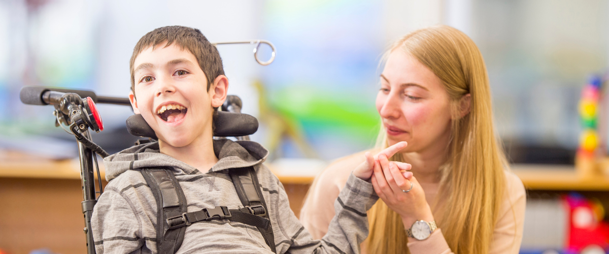 young man in wheelchair with therapist or teacher