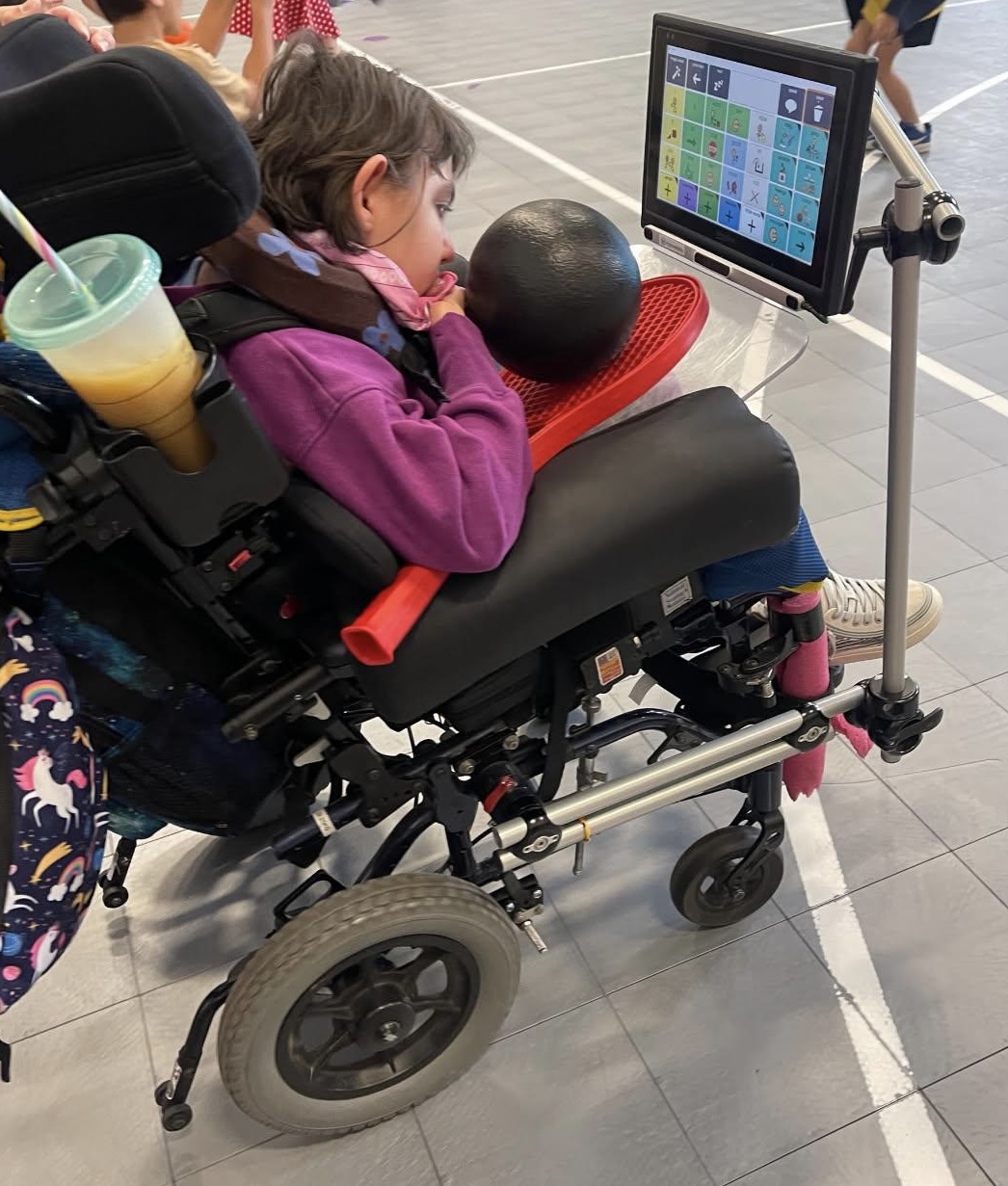 child in wheelchair using a tablet for communication