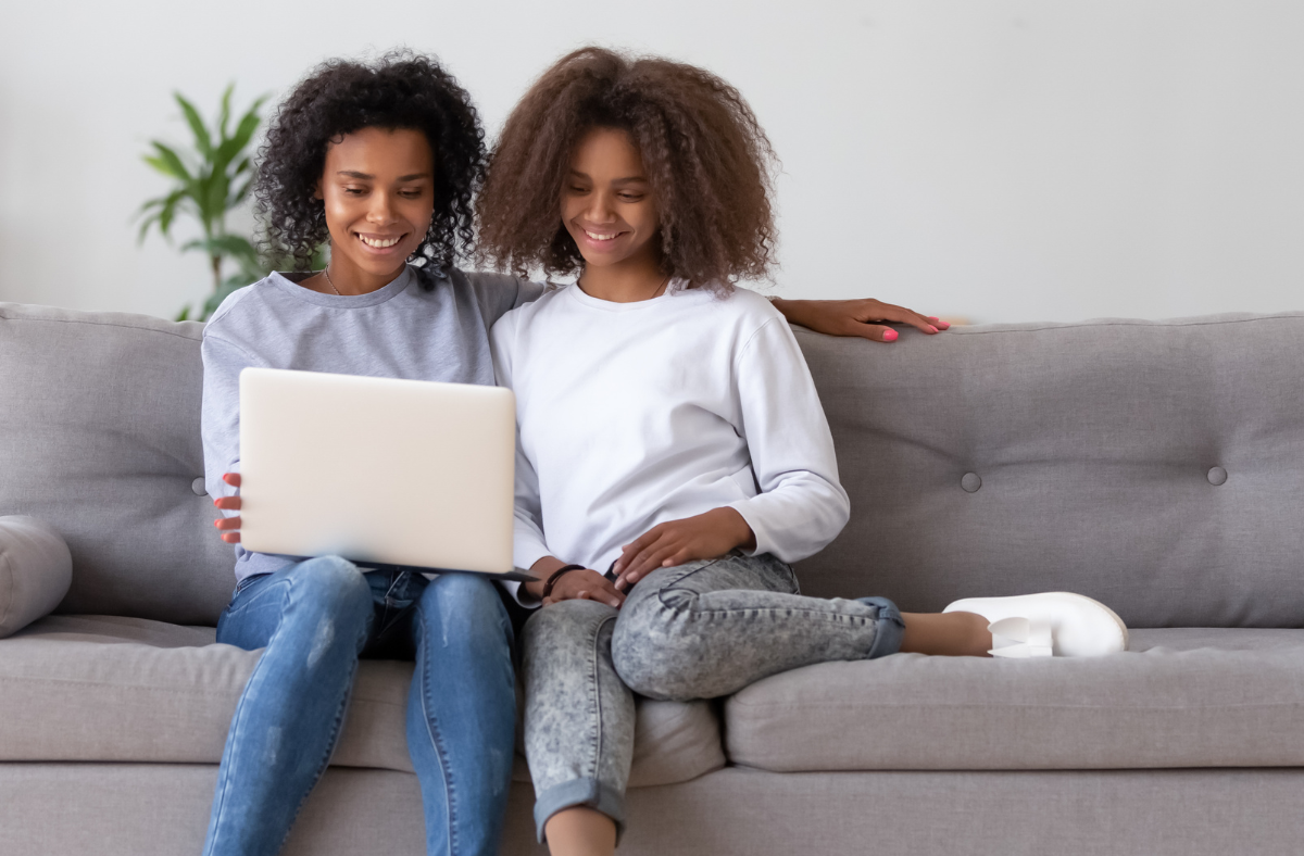teen sitting on couch with mom looking at laptop together