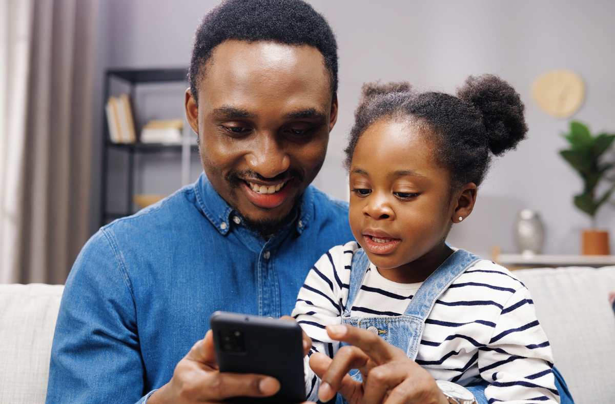 father and young daughter looking at phone together
