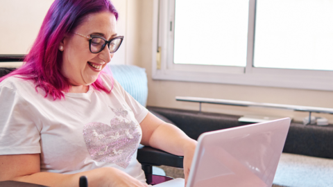 young woman sitting in wheelchair looking at laptop