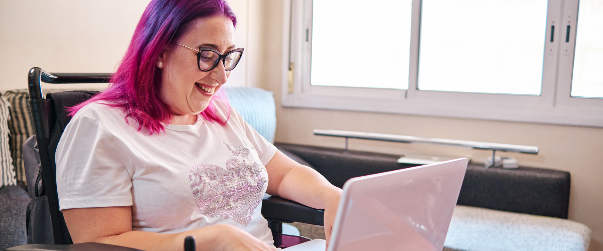 young woman sitting in wheelchair looking at laptop