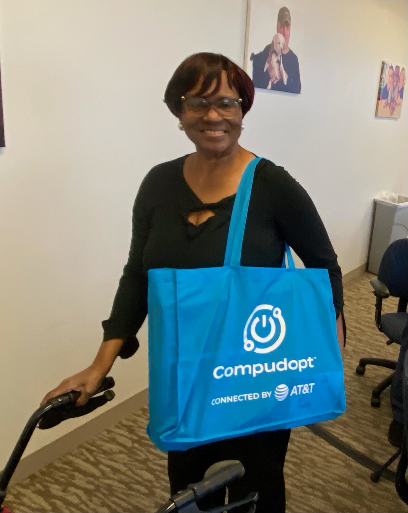 lady standing in front of walker smiling at camera with blue bag on her shoulder that says Compudopt
