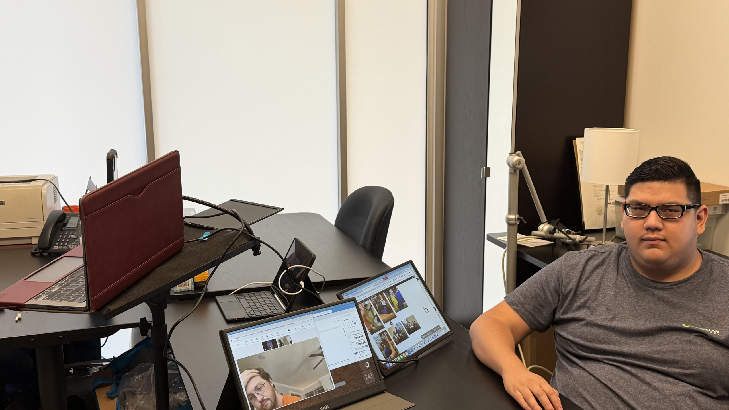 young man sitting at desk with 2 laptops open in front of him